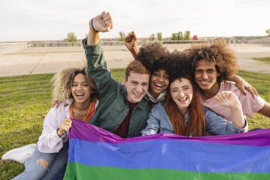 Genç insanlar dışarıda LGBT gökkuşağı bayrağı tutarken eğleniyorlar.