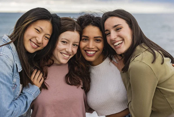 Diversity, multi-ethnic beauty concept. Four beautiful smiling ladies of different races, Hispanic, Asian and Caucasian, natural, posing on the sea background