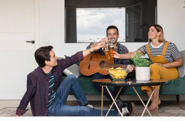 Bir grup genç arkadaşın portresi evde gitar, patates birası ve ev partisiyle eğleniyor.