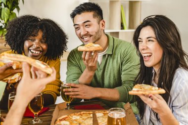 Restoranda sosyalleşen bir grup çok ırklı genç iş arkadaşı. Pizza yemek ve bira içmek. Arkadaşlarla yemek yemek.-