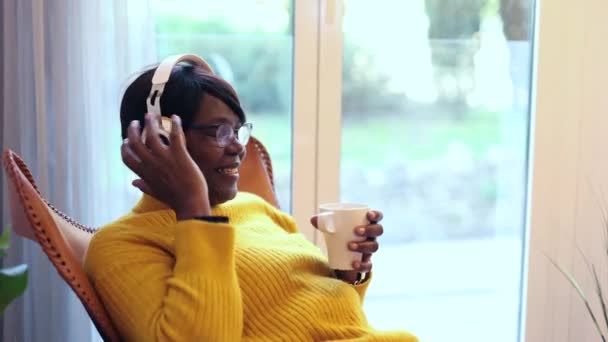 Kulaklıklı Güzel Bir Afrikalı Kadının Portresi Pencereye Bakıp Bir Kupadan — Stok video
