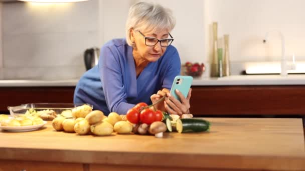 Senior Mujer Cocina Miradas Teléfono Inteligente Receta — Vídeo de stock