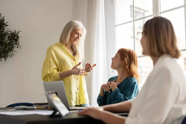 stock image Three cheerful businesswomen in an office. Diverse group of businesswomen smiling while discussing. Successful female colleagues collaborating on a new project.