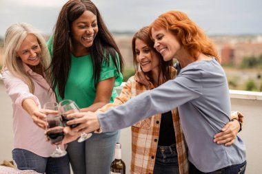 group of multiracial female friends of different ages partying on the rooftop and toasting with wine - multigenerational - clipart