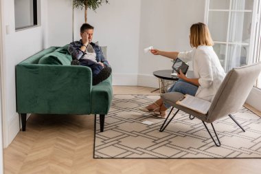 Genç bir adamın boşanması, danışmanın ofisinde koltukta oturması, yüzüne dokunması, obez kadın psikologla terapi seansına katılması. Stres ve endişe terapisi. ruh sağlığı