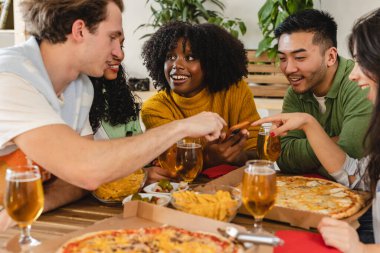 Bir grup çok ırklı arkadaş bir kanepede pizza yiyor ve bir ev partisinde meşrubat içiyor, genç adam elinde pizza kutusuyla sokaklardan geliyor.