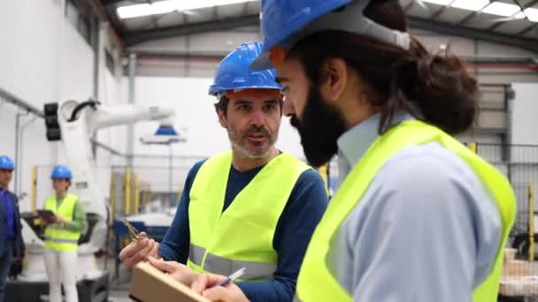 带着防护头盔和反光背心 说话和工作的工厂的同事 — 图库视频影像