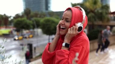 pretty mature woman with shaved hair wearing headphones on the street dancing listens to music