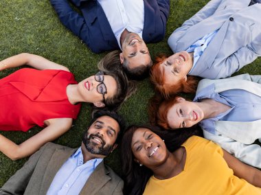 Çimlerin üzerinde yatan çok ırklı iş adamları