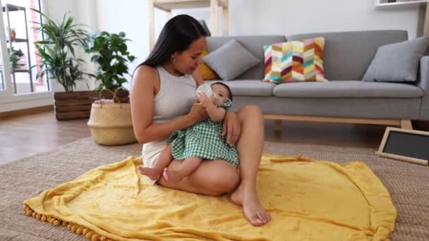 Новая Латиноамериканская Мать Кормит Ребенка Бутылкой Сидя Ковре Гостиной Дома — стоковое видео