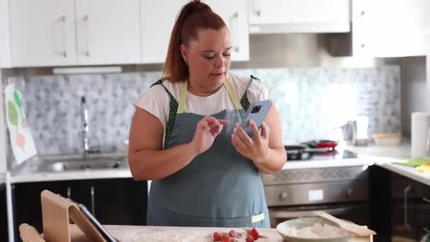 Kurvige Frau Bereitet Hause Essen Während Sie Ihr Smartphone Kontrolliert — Stockvideo