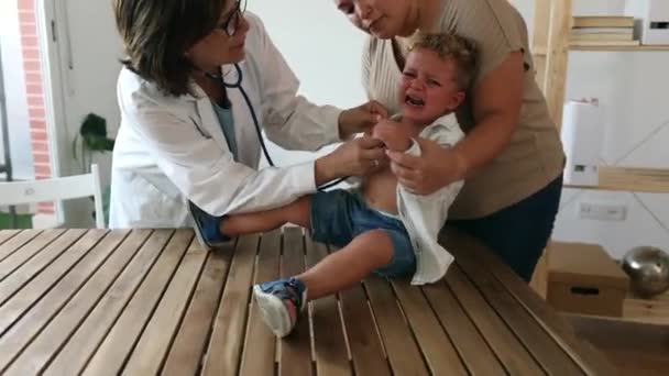 Female Senior Pediatrician Doctor Listening Crying Little Boy Next His — Stock Video
