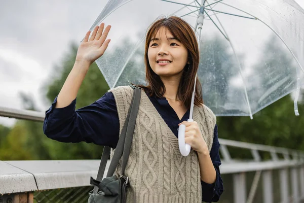 asian woman greeting a rainy day with umbrella