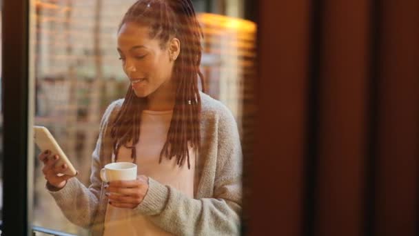 アフリカ系アメリカ人女性が自宅のバルコニーでコーヒーとスマートフォンで — ストック動画