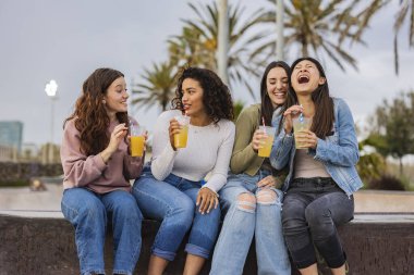 Milenyum kadınları tatil için şehir parkında kokteyl içiyor.