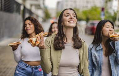 Dışarıda pizza yiyen dört farklı genç, çok ırklı arkadaş. Şehirde sokak yemeklerinden hoşlanan mutlu kadınlar. İtalyan yemek kültürü ve Avrupa tatil kavramı.