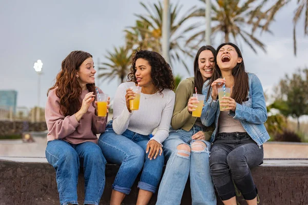 millennial generation women on vacation drinking cocktails in city park
