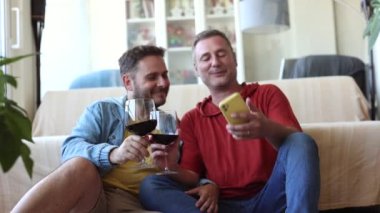 Eşcinsel çift tatlı bir selfie çektiler. Evde bir kadeh şarapla sarılıp, aşklarını ve birlikteliklerinin basit zevklerini kutlarken şefkatli bir öpücük yakaladılar.