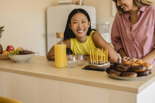 diverse friends celebrating birthday with cake with candles, asian woman smiling looking at camera