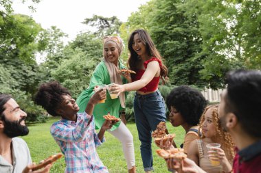 Çeşitli etnik çeşitlilikte kadınlar piknik partisinde birlikte eğleniyorlar.