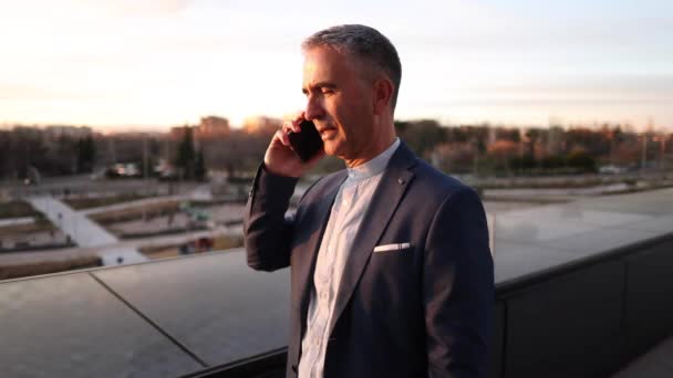 都市の携帯電話で話している夕日屋外で成熟したビジネスマン — ストック動画