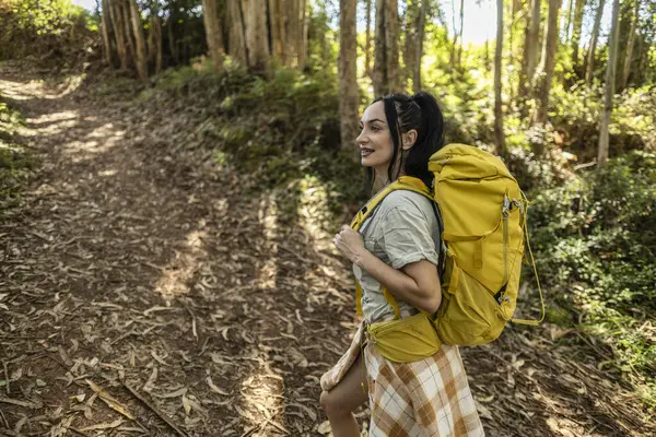 backpacker woman trekking through the forest path