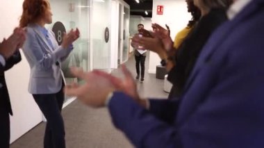 Bir grup çok ırklı iş adamı, meslektaşlarının terfisini alkışlıyor.