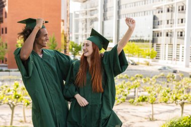 Mezuniyet gününde nitelikli öğrenciler. Cüppeli öğrenciler törende telefonla selfie çekiyorlar. Hatırlanmaya değer çok ırklı mezunlar akademik başarıları ve kilometre taşlarını kutluyor..