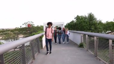 Sırt çantasıyla yürüyen bir çocuğa zorbalık eden bir grup öğrenci.