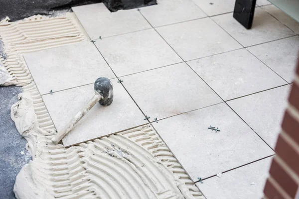 Tiler placing the ceramic tile on the floor. Grouting ceramic tiles. renewal. Construction. Tiler\'s hands. Home renovation and construction of new houses.
