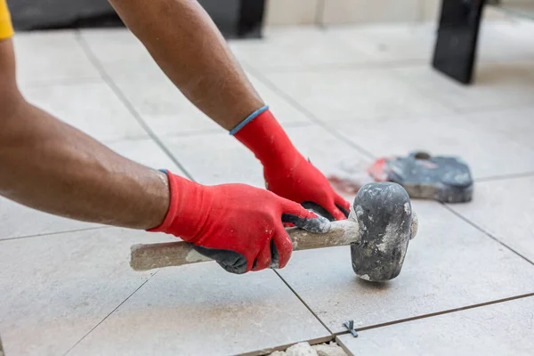 bricklayer tiling the floor of the terrace with a hammer