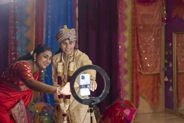 young indian couple in traditional clothes practicing dance recording video social media - streaming influencer -