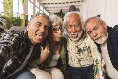Bir grup kıdemli arkadaş akıllı bir cep telefonu cihazıyla selfie çekiyorlar - emeklilerin birlikte eğlendiği yaşam tarzı konsepti.