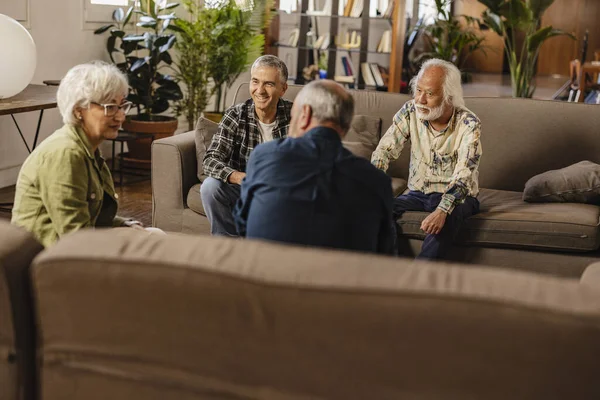 group of multiracial senior friends talk about their friendship in their living room