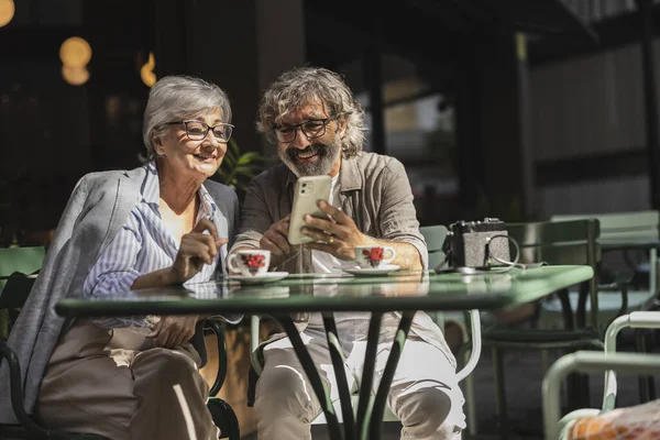 attractive retired couple have a date for Valentine\'s Day, they look at their phone looking at photos and remembering moments together