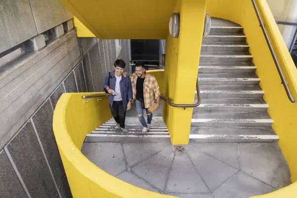 Stock image two friends walking up colorful stairs in London while laughing