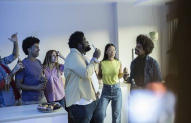 Bir grup mutlu çok ırklı arkadaş dairedeki bir parti sırasında karaoke yapıyor, kadeh kaldırıyor ve tezahürat yapıyorlar.