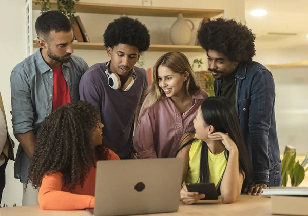 group of young multiracial students in front of laptop doing a project for college class