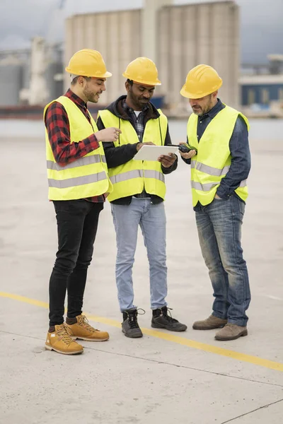 stock image Vertical photograph of multiracial group of men working in the harbor with their walkie talkies and graphics tablets