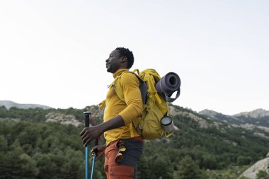 Afrikalı bir Amerikalı bir dağın tepesinde dururken dağların manzarasından zevk alır..