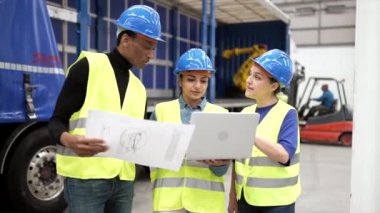 Dizüstü bilgisayar ve dijital tablet, takım çalışması ve sinerji konseptini kullanarak yeni gelen malları kontrol ve analiz etmek için çalışan fabrika işçileri veya mühendis işçileri