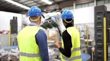 Baş mühendis ve proje yöneticisi güvenlik yeleği ve miğfer giyer, üretkenliği artırmak için yeni işçi ve program makineleriyle selamlaşır ve konuşurlar..