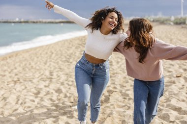 Çok kültürlü arkadaşlar birbirlerine sarılıyorlar plajda birlikte koşuyorlar.