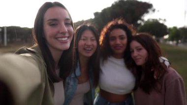 Neşeli bir grup gencin gülümseyen selfie 'si. Heyecanlı mutlu arkadaşların eğlendiği bir video. Irklar arası kızlar cep telefonu kameralarına bakarak fotoğraf çekiyorlar. Tatilin tadını çıkarıyorum.