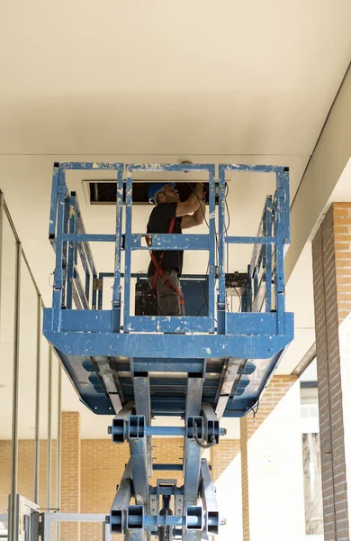 Network engineer installing cable equipment in rack in building, with a crane