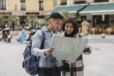 Sevgililer Günü gezilerinde haritaya bakan çok ırklı genç bir çift.