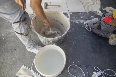 Teras döşemek için kovada çimento yapan işçi.