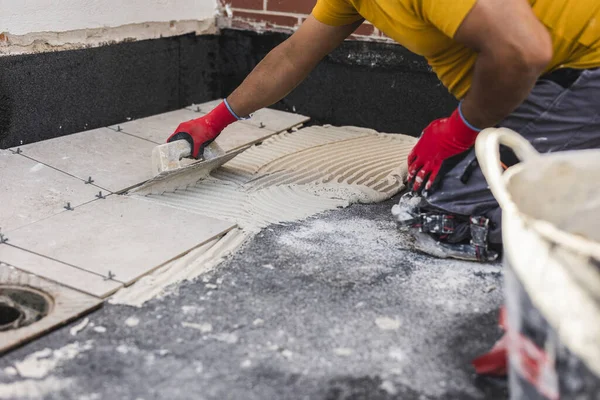 worker laying tiles on the floor with cement