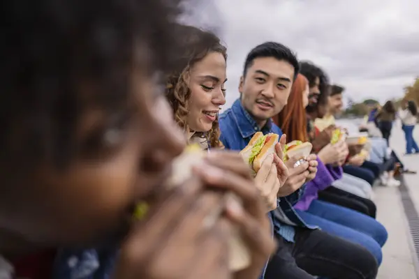multiethnic friends placed in line having snack, focus is on young woman