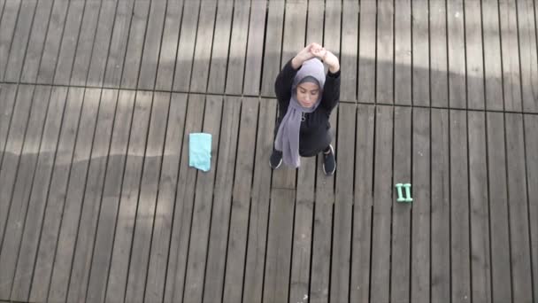 屋外に小さなダンベルを持ち上げるスポーツウェアを着ているヒジャーブのイスラム教徒の女性 — ストック動画